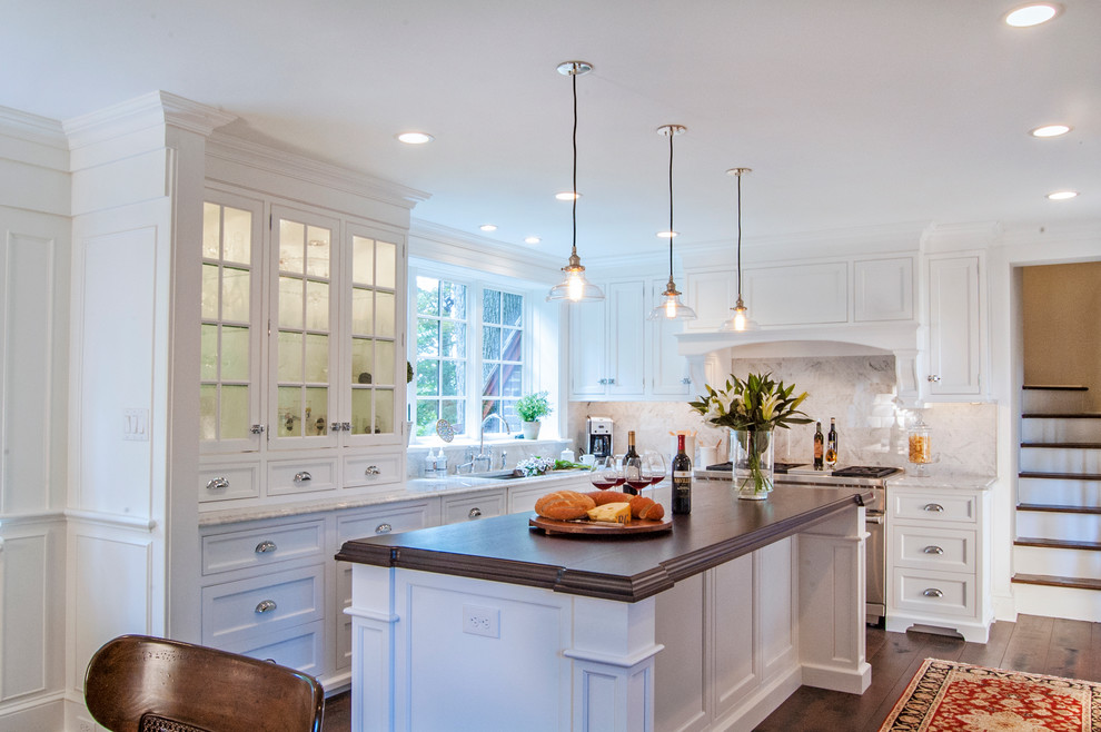 This is an example of a large traditional l-shaped eat-in kitchen in Philadelphia with an undermount sink, white cabinets, wood benchtops, white splashback, stone tile splashback, stainless steel appliances, dark hardwood floors, with island and recessed-panel cabinets.