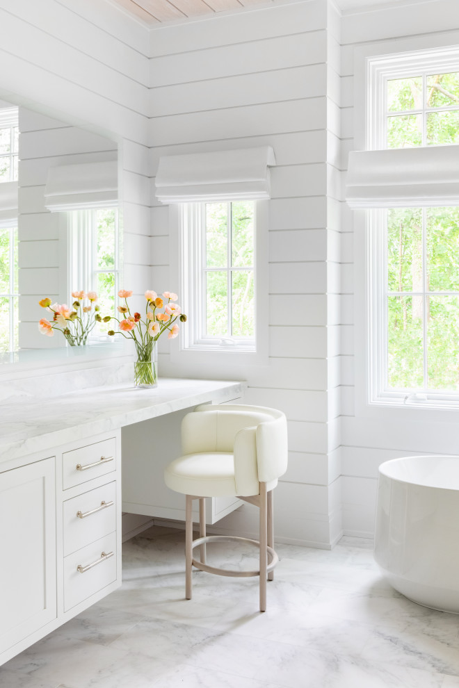 Huge transitional master marble floor, white floor, double-sink, vaulted ceiling and wall paneling bathroom photo in New York with beaded inset cabinets, white cabinets, white walls, an integrated sink, marble countertops, a hinged shower door, white countertops and a built-in vanity