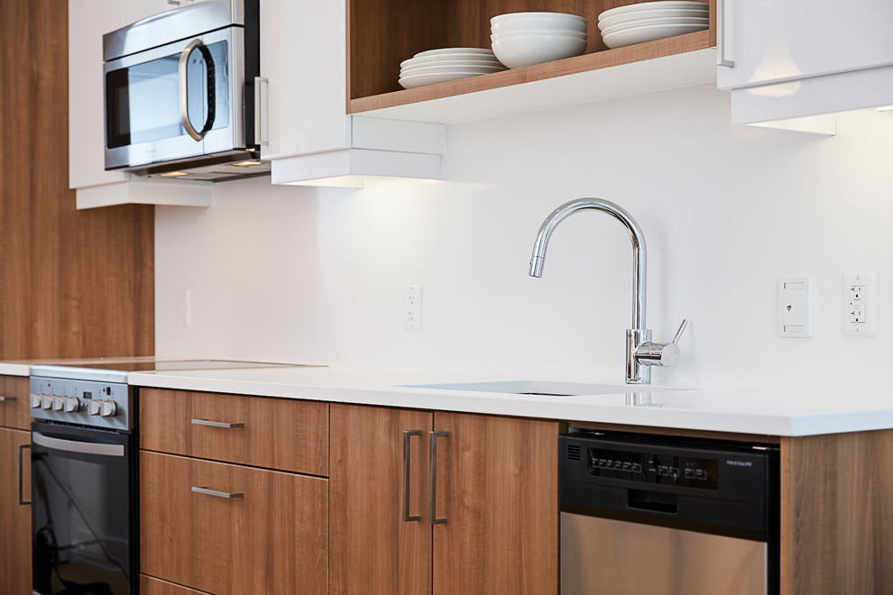 Photo of a contemporary single-wall eat-in kitchen in Ottawa with an undermount sink, flat-panel cabinets, white cabinets, white splashback, stainless steel appliances, medium hardwood floors and no island.
