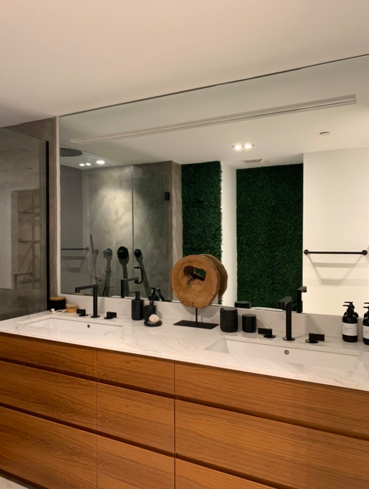 This is an example of a large modern master bathroom in Miami with medium wood cabinets, a one-piece toilet, black tile, porcelain tile, white walls, concrete floors, an undermount sink, marble benchtops, grey floor, a hinged shower door, white benchtops and flat-panel cabinets.