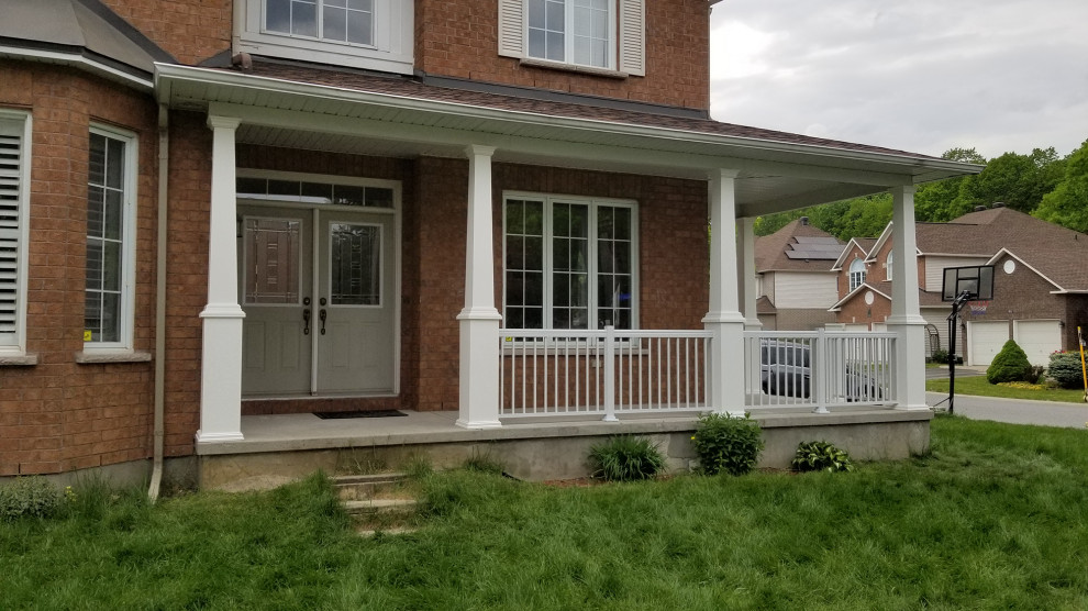 This is an example of a large modern front yard verandah in Ottawa with with columns, concrete slab, a roof extension and metal railing.