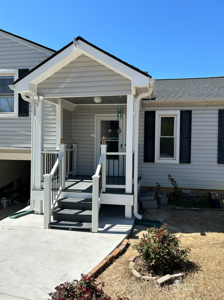 Cette photo montre un petit porche d'entrée de maison avant chic avec une dalle de béton, une extension de toiture et un garde-corps en matériaux mixtes.