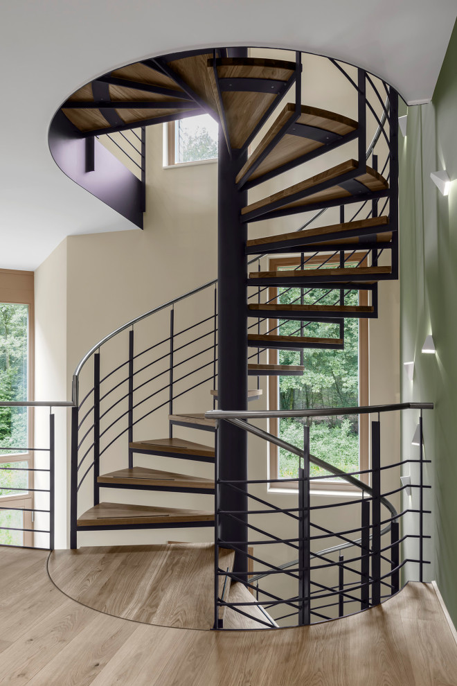 Aménagement d'un grand escalier hélicoïdal contemporain avec des marches en bois et un garde-corps en métal.