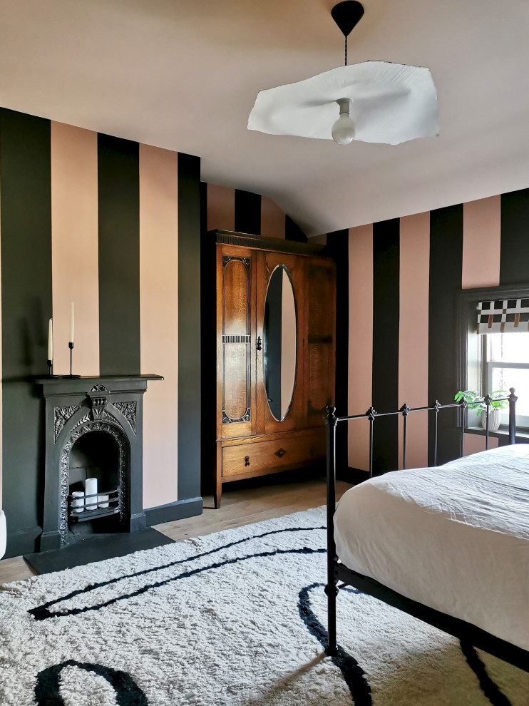 Cette image montre une chambre d'amis nordique de taille moyenne avec un mur multicolore, parquet clair, une cheminée standard, un manteau de cheminée en métal, un sol beige et du papier peint.