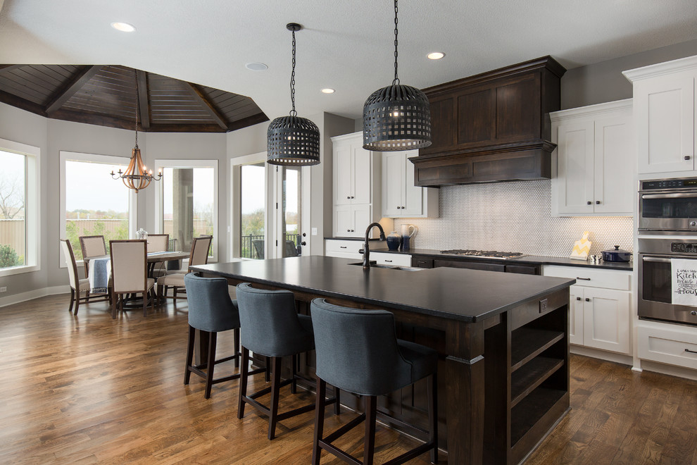 Design ideas for a transitional eat-in kitchen in Kansas City with shaker cabinets, white cabinets, white splashback, stainless steel appliances, medium hardwood floors and with island.