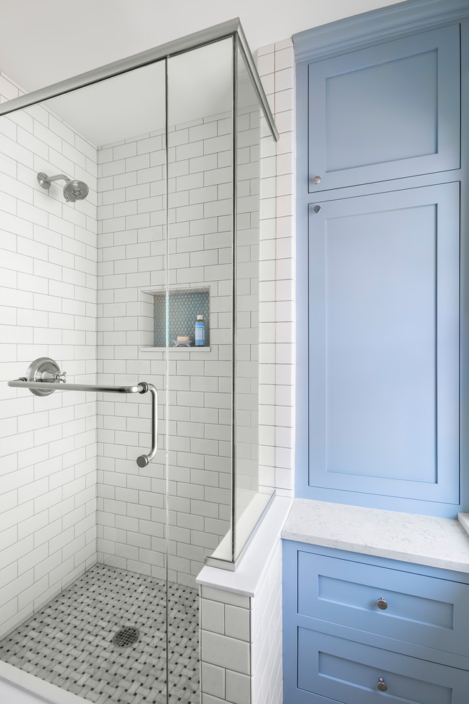 Photo of a small traditional bathroom in Minneapolis with blue cabinets, a corner shower, a two-piece toilet, black and white tile, ceramic tile, blue walls, marble floors, an undermount sink, engineered quartz benchtops, grey floor, a hinged shower door, white benchtops and shaker cabinets.