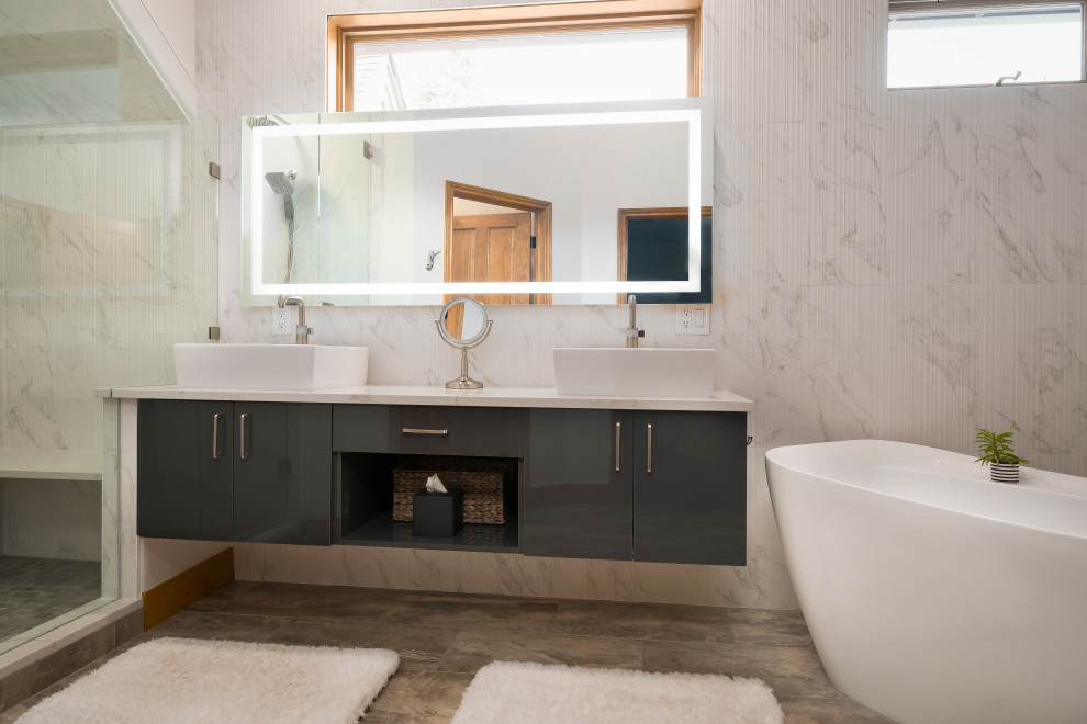Inspiration pour une grande salle de bain principale design avec un placard à porte plane, des portes de placard grises, une baignoire indépendante, meuble double vasque et meuble-lavabo suspendu.