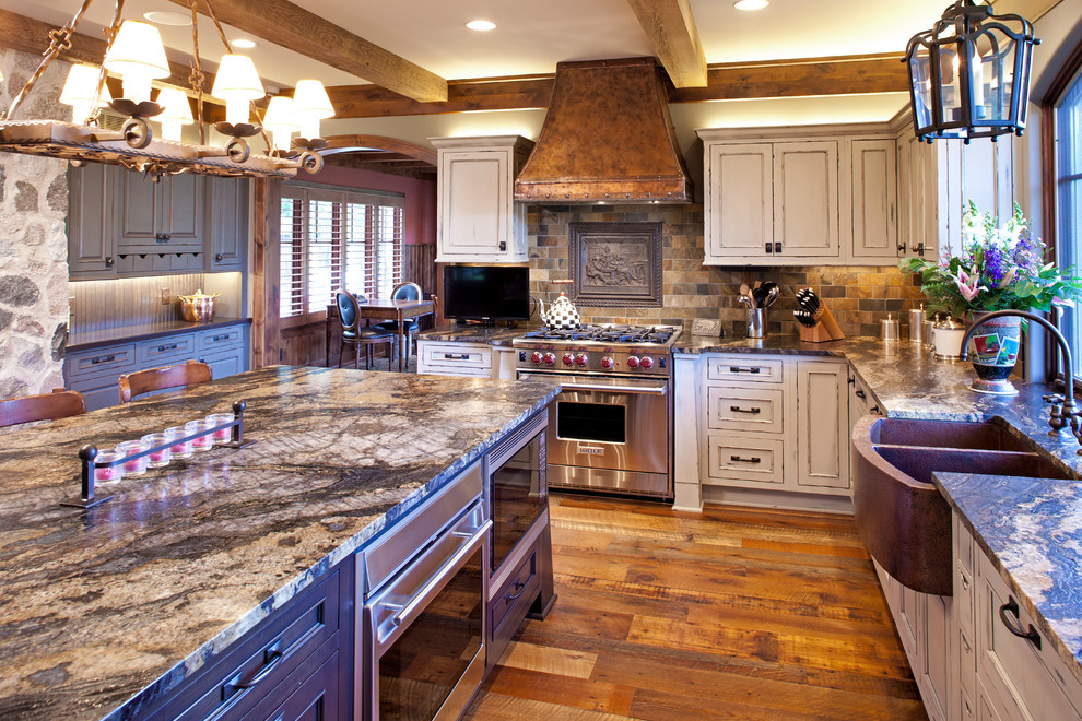 This is an example of a large l-shaped eat-in kitchen in Minneapolis with recessed-panel cabinets, distressed cabinets, granite benchtops, multi-coloured splashback, medium hardwood floors, with island, a farmhouse sink and stainless steel appliances.