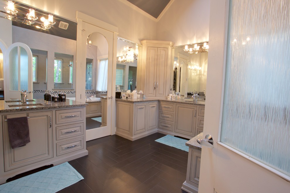 Example of a huge transitional master beige tile dark wood floor corner bathtub design with an undermount sink, beaded inset cabinets, gray cabinets, granite countertops and beige walls