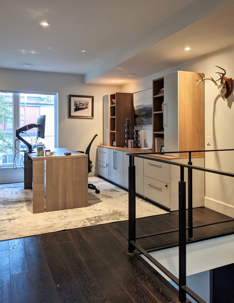 Diseño de despacho moderno de tamaño medio con paredes grises, suelo de madera oscura, escritorio independiente y suelo marrón