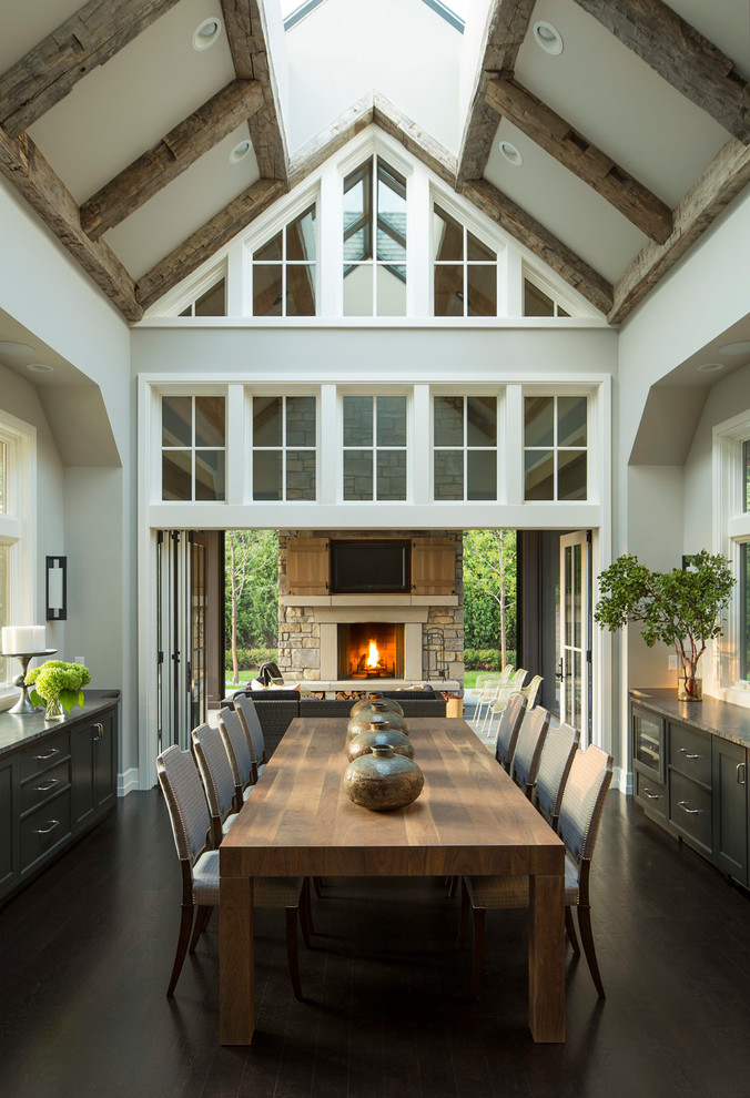 Inspiration for a transitional separate dining room in Minneapolis with grey walls, dark hardwood floors and a stone fireplace surround.