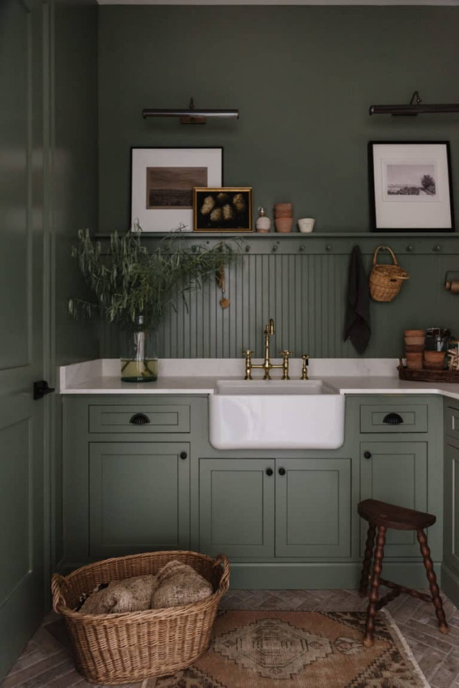 Cette image montre une buanderie avec un évier de ferme, un placard à porte shaker, plan de travail en marbre, une crédence verte, un mur vert, un sol en carrelage de porcelaine et un plan de travail vert.
