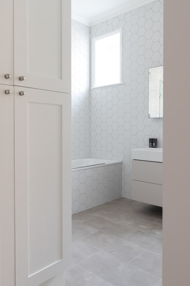 Стильный дизайн: детская, серо-белая ванная комната среднего размера в стиле модернизм с плоскими фасадами, серыми фасадами, накладной ванной, душем над ванной, белой плиткой, монолитной раковиной, серым полом, душем с распашными дверями, тумбой под одну раковину и подвесной тумбой - последний тренд