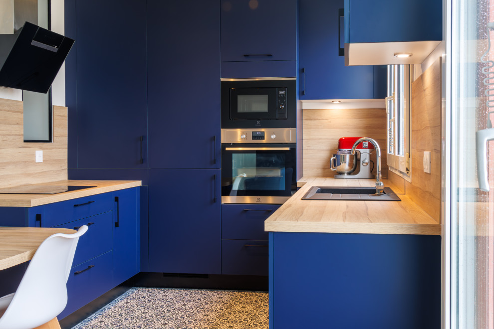 Idéer för ett litet modernt beige kök, med en undermonterad diskho, luckor med infälld panel, blå skåp, träbänkskiva, beige stänkskydd, stänkskydd i trä, integrerade vitvaror, cementgolv och blått golv