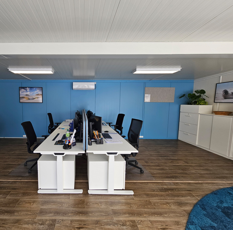 Mid-sized beach style study room in Other with blue walls, dark hardwood floors, a freestanding desk and brown floor.