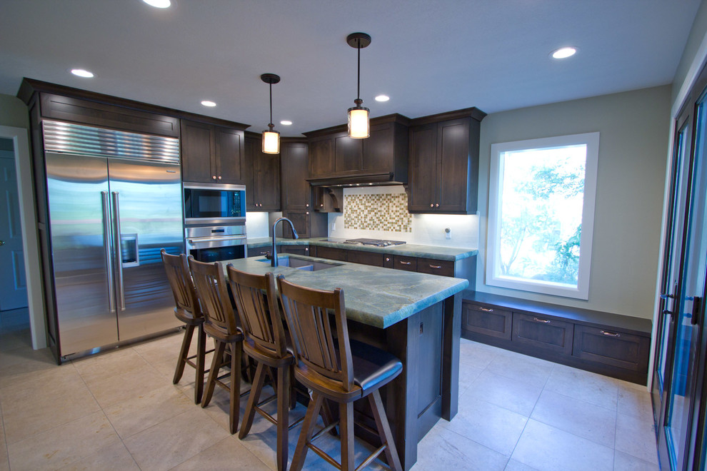 Photo of a mid-sized transitional l-shaped eat-in kitchen in Salt Lake City with a double-bowl sink, shaker cabinets, dark wood cabinets, quartzite benchtops, white splashback, stone tile splashback, stainless steel appliances, limestone floors and with island.