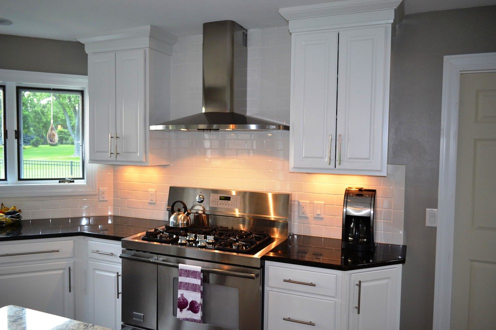 Mid-sized transitional dark wood floor open concept kitchen photo with raised-panel cabinets, white cabinets, granite countertops, white backsplash, subway tile backsplash, stainless steel appliances and an island