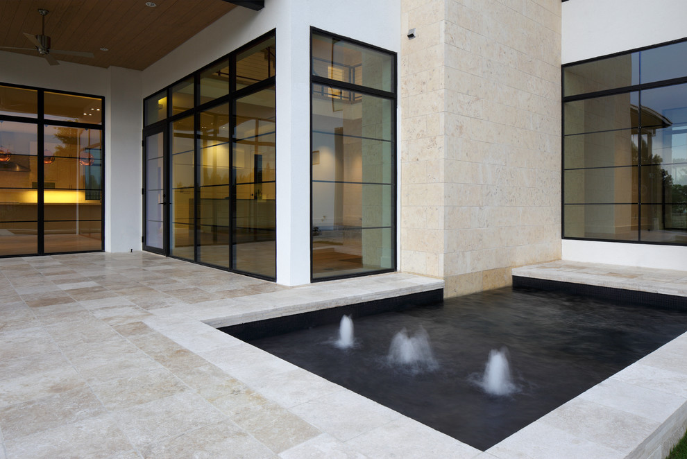 This is an example of a mid-sized modern backyard rectangular lap pool in Dallas with a water feature and tile.