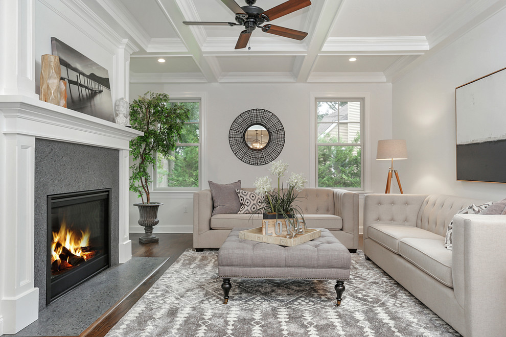 Photo of a transitional formal living room in New York with white walls, dark hardwood floors, a standard fireplace, a stone fireplace surround, no tv and brown floor.