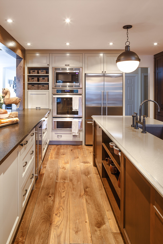 Photo of a mid-sized traditional u-shaped eat-in kitchen in Ottawa with a drop-in sink, dark wood cabinets, grey splashback, stainless steel appliances, medium hardwood floors and with island.