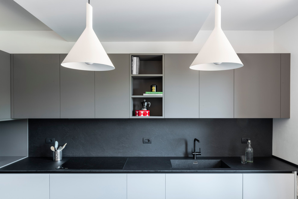 Design ideas for a large modern l-shaped separate kitchen in Milan with flat-panel cabinets, black splashback, no island, grey floor and black benchtop.