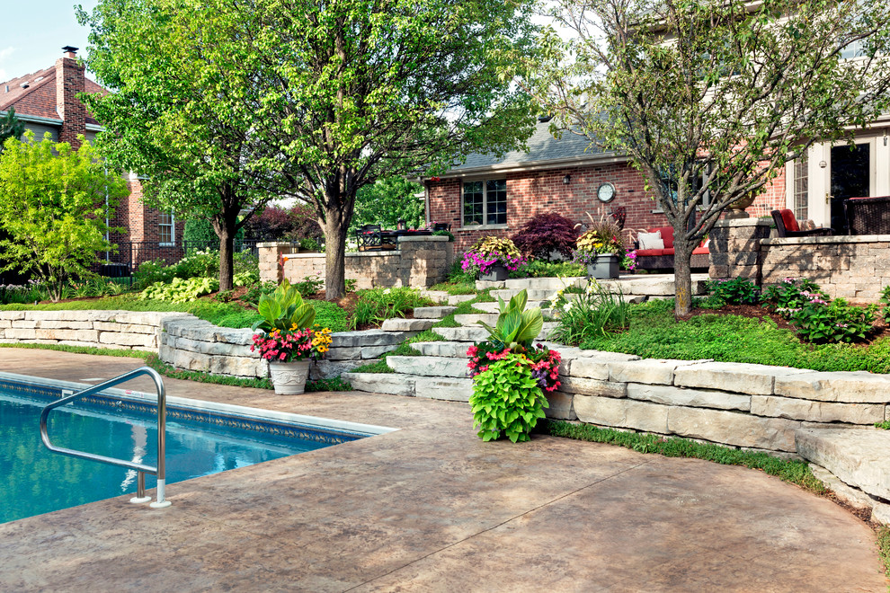 Mid-sized transitional backyard full sun garden in Chicago with a retaining wall and natural stone pavers for summer.