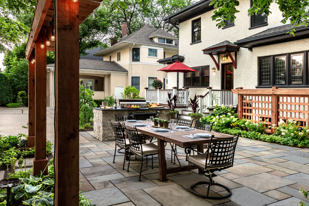 Design ideas for a large traditional backyard patio in Chicago with natural stone pavers and no cover.