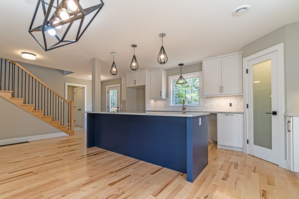 Inspiration for a mid-sized transitional light wood floor and beige floor eat-in kitchen remodel with an undermount sink, shaker cabinets, white cabinets, granite countertops, white backsplash, ceramic backsplash, an island and gray countertops