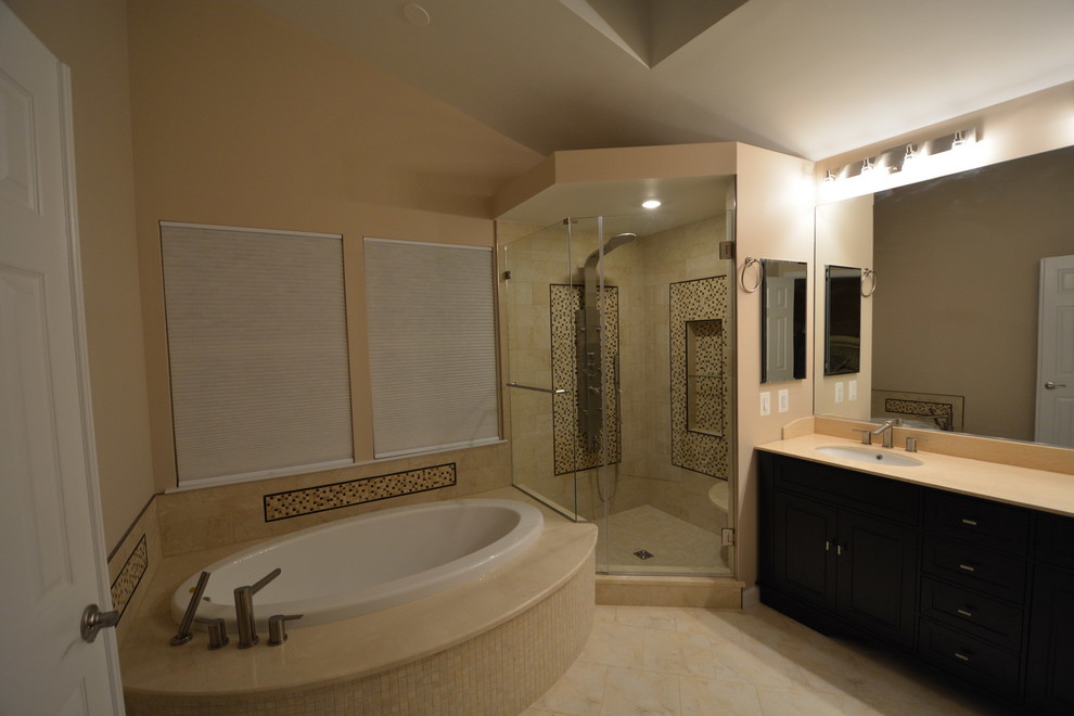 Inspiration for a large transitional master beige tile and stone tile marble floor and beige floor drop-in bathtub remodel in Baltimore with dark wood cabinets, a two-piece toilet, beige walls, an undermount sink, beaded inset cabinets, solid surface countertops, a hinged shower door and beige countertops