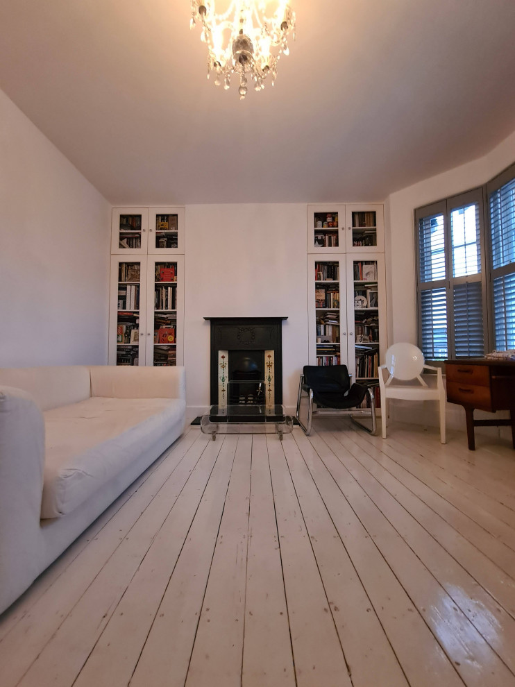 Photo of a mid-sized traditional open concept living room in London with a music area, white walls, painted wood floors, a standard fireplace, a metal fireplace surround, a freestanding tv, white floor and recessed.