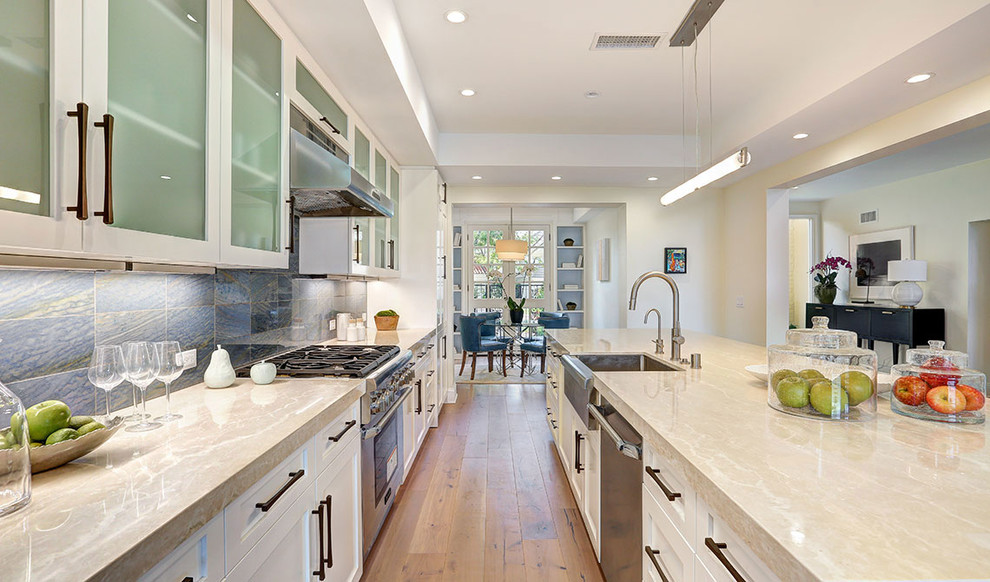 Inspiration for a large transitional u-shaped eat-in kitchen in Los Angeles with a single-bowl sink, shaker cabinets, white cabinets, quartzite benchtops, black splashback, stone tile splashback, stainless steel appliances, medium hardwood floors, with island, brown floor and beige benchtop.