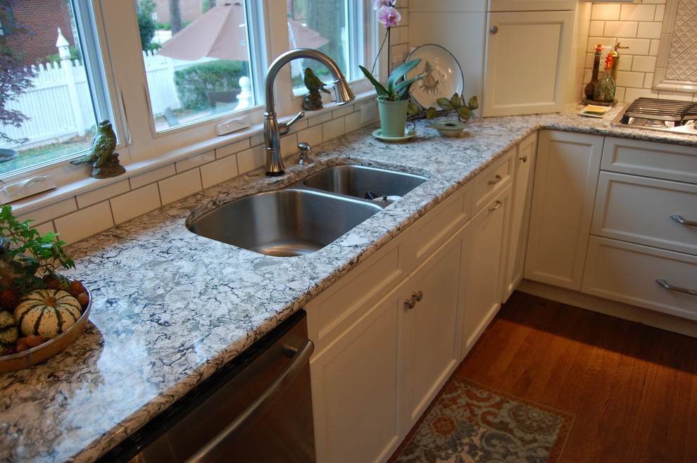 Example of a transitional u-shaped eat-in kitchen design in Raleigh with an undermount sink, recessed-panel cabinets, white cabinets, quartzite countertops, white backsplash, subway tile backsplash and stainless steel appliances