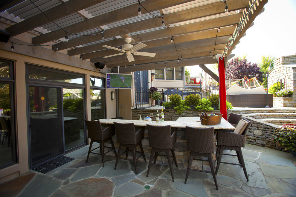 This is an example of a mid-sized transitional backyard patio in Salt Lake City with a pergola and natural stone pavers.