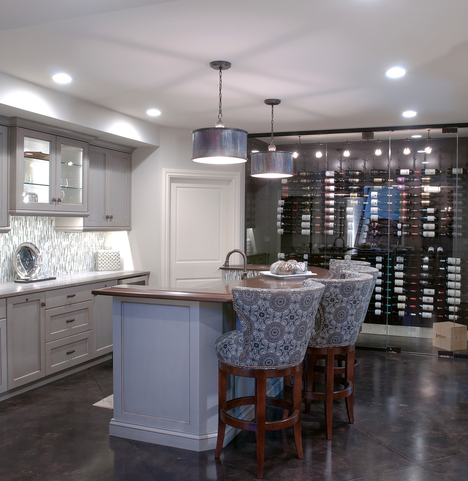 This is an example of a large mediterranean galley seated home bar in Grand Rapids with an undermount sink, recessed-panel cabinets, grey cabinets, granite benchtops, multi-coloured splashback, matchstick tile splashback and concrete floors.