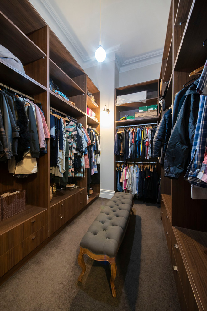 Photo of a large beach style gender-neutral walk-in wardrobe in Melbourne with open cabinets, dark wood cabinets, carpet and grey floor.