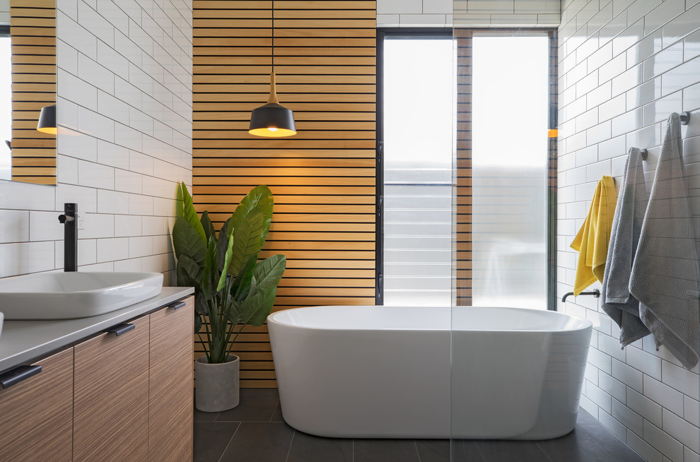 Mid-sized contemporary bathroom in Adelaide with flat-panel cabinets, light wood cabinets, a freestanding tub, an open shower, white tile, subway tile, white walls, a vessel sink, grey floor and an open shower.