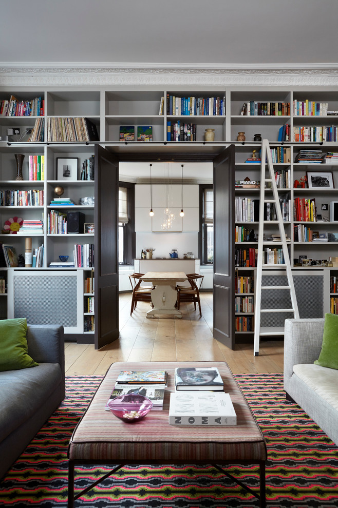 Transitional living room in London with a library.