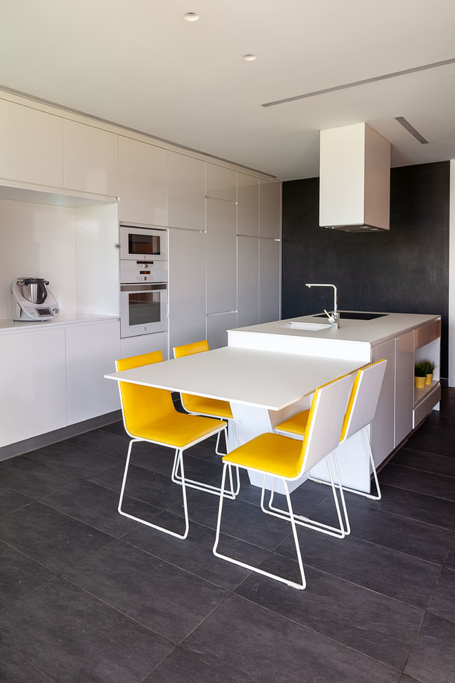 Inspiration for a contemporary galley eat-in kitchen in Other with an undermount sink, flat-panel cabinets, white cabinets, white splashback, white appliances, with island, grey floor and white benchtop.