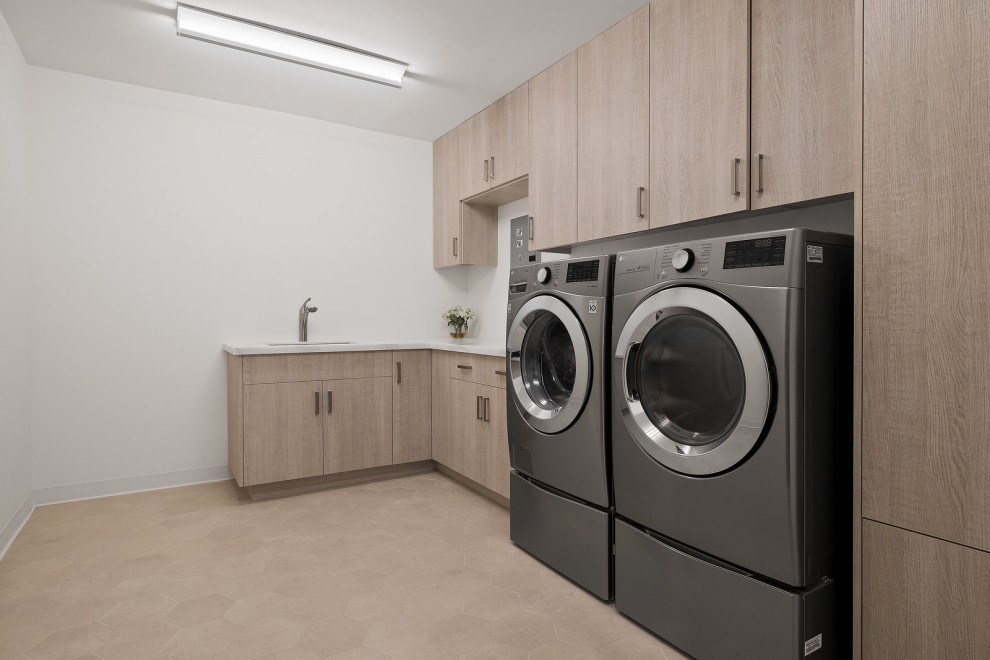 Photo of a mid-sized modern u-shaped laundry cupboard in Los Angeles with an utility sink, marble benchtops, white walls, an integrated washer and dryer, beige floor and beige benchtop.