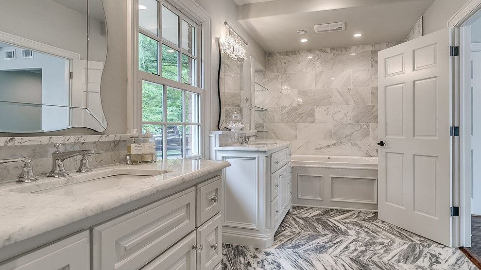 This is an example of a country master bathroom in Oklahoma City with raised-panel cabinets, white cabinets, a drop-in tub, marble, grey walls, marble floors, an undermount sink and marble benchtops.