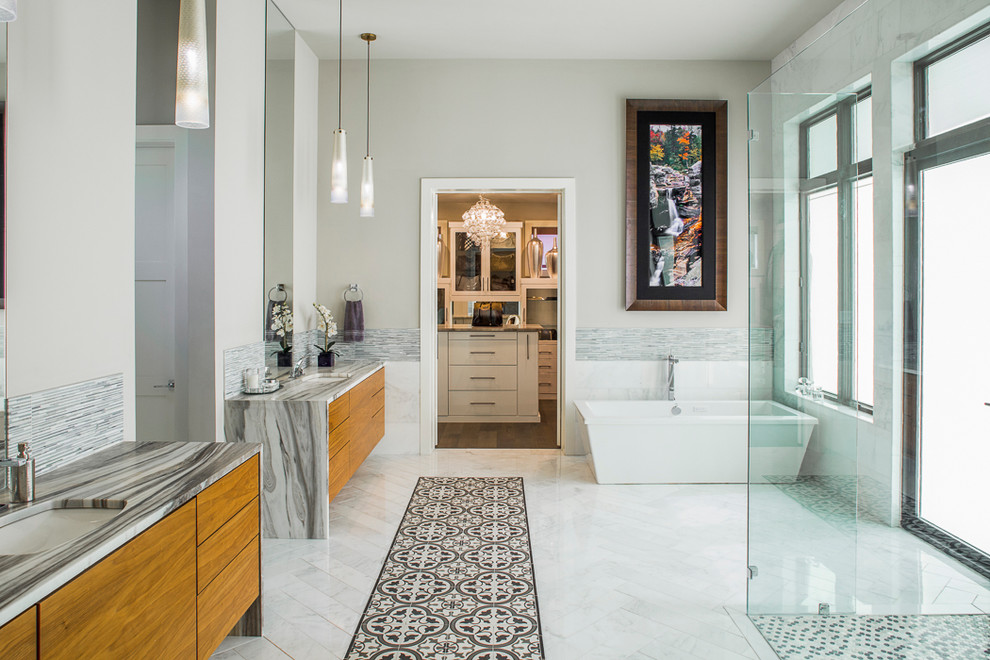 Design ideas for a contemporary master bathroom in Austin with flat-panel cabinets, medium wood cabinets, marble benchtops, multi-coloured tile, matchstick tile, a freestanding tub, a curbless shower, an undermount sink, grey walls and marble floors.