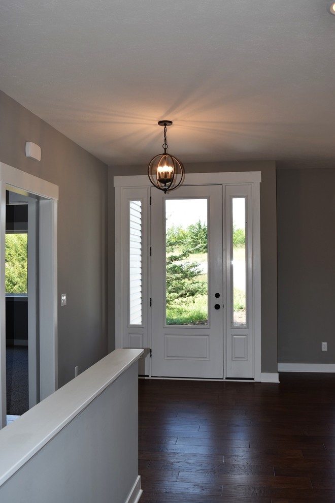 Mid-sized transitional medium tone wood floor and brown floor front door photo with gray walls and a white front door