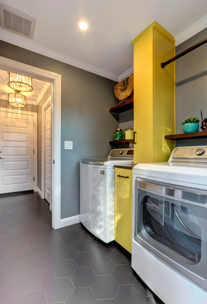 Foto di una piccola lavanderia boho chic con ante lisce, ante gialle, top in legno, pareti grigie, pavimento in gres porcellanato, lavatrice e asciugatrice affiancate e pavimento nero