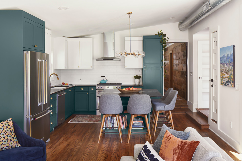 Open concept kitchen - mid-sized contemporary l-shaped medium tone wood floor and brown floor open concept kitchen idea in Austin with an undermount sink, shaker cabinets, green cabinets, soapstone countertops, white backsplash, ceramic backsplash, stainless steel appliances, an island and black countertops