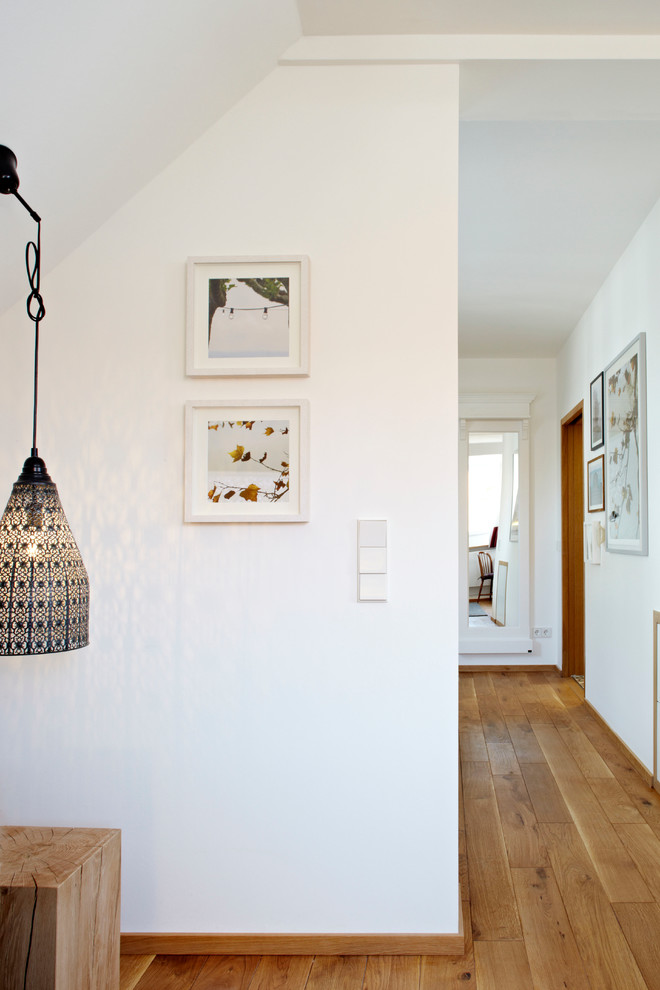 This is an example of a contemporary hallway in Munich with white walls and medium hardwood floors.