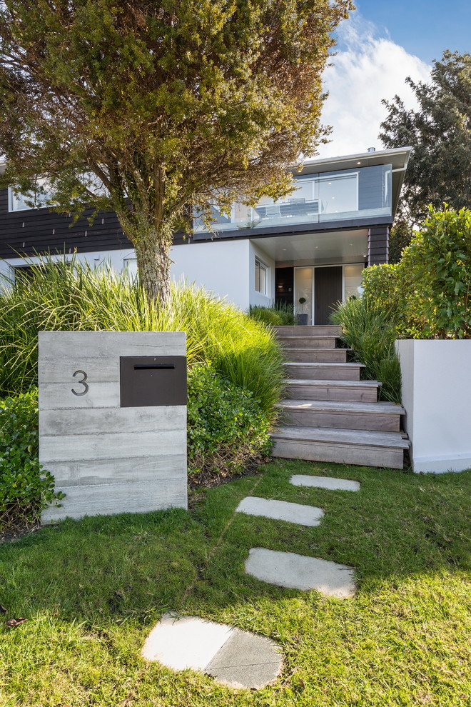 Large contemporary two-storey black house exterior in Auckland with wood siding, a flat roof and a metal roof.