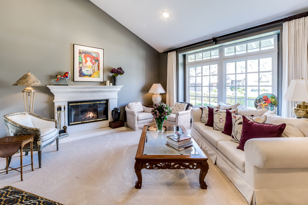 This is an example of a mid-sized transitional formal open concept living room in Los Angeles with grey walls, carpet, a standard fireplace, a plaster fireplace surround and no tv.