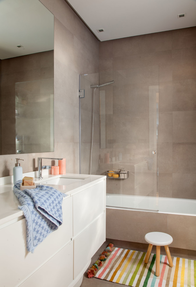 Contemporary bathroom in Bilbao with flat-panel cabinets, beige cabinets, a drop-in tub, a shower/bathtub combo, brown tile, brown walls, an undermount sink, brown floor and beige benchtops.