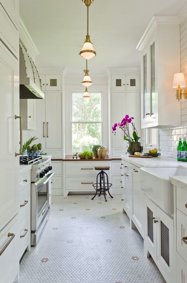 Small traditional galley separate kitchen in Austin with a farmhouse sink, recessed-panel cabinets, white cabinets, marble benchtops, white splashback, subway tile splashback, panelled appliances, porcelain floors and no island.