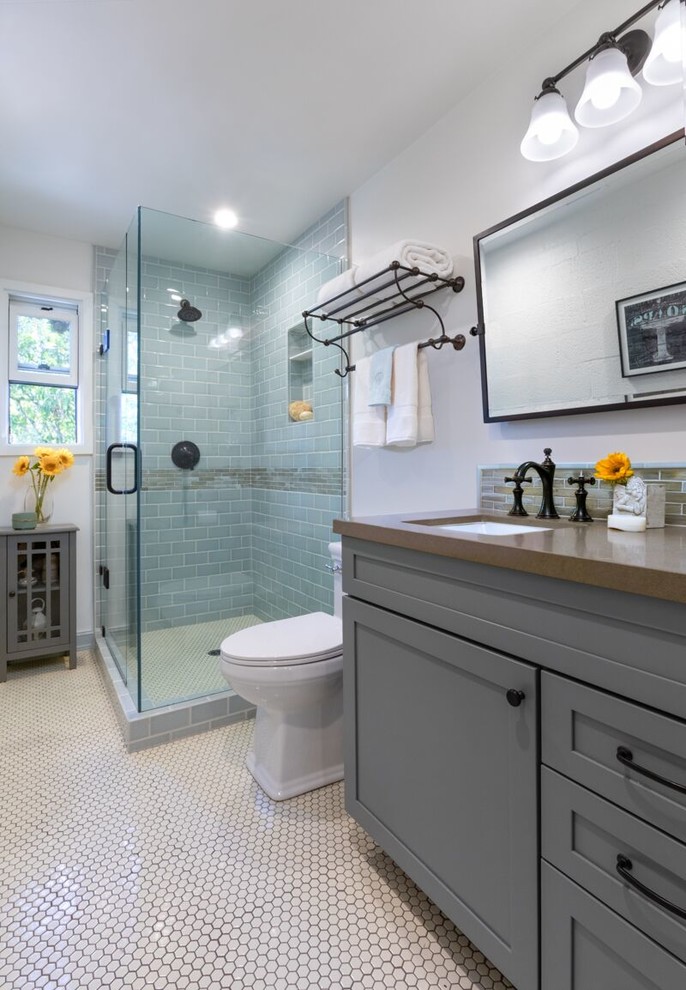 This is an example of a mid-sized beach style master bathroom in Santa Barbara with flat-panel cabinets, grey cabinets, a corner shower, a one-piece toilet, blue tile, ceramic tile, blue walls, ceramic floors, a drop-in sink, quartzite benchtops, white floor, a hinged shower door and brown benchtops.